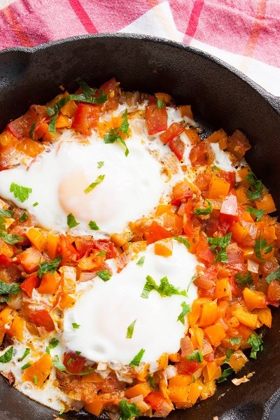 Shakshuka - poached eggs dish with spicy tomatoes, peppers and onions